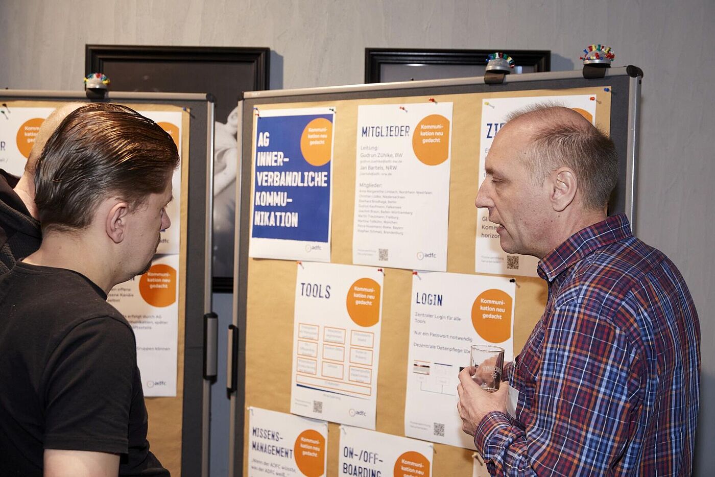 45. ADFC-Bundeshauptversammlung 2025 Zwei Männer unterhalten sich vor Pinnwänden mit Informationsplakaten.