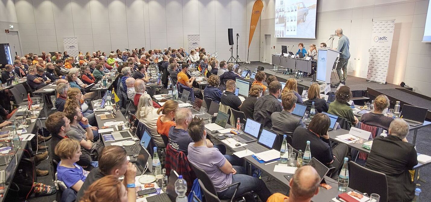 von Heesen Ein grpßer Saal mit 140 Menschen an Tischreihen, die zur Bühne blicken, wo Boris von Heesen einen Vortrag hält.