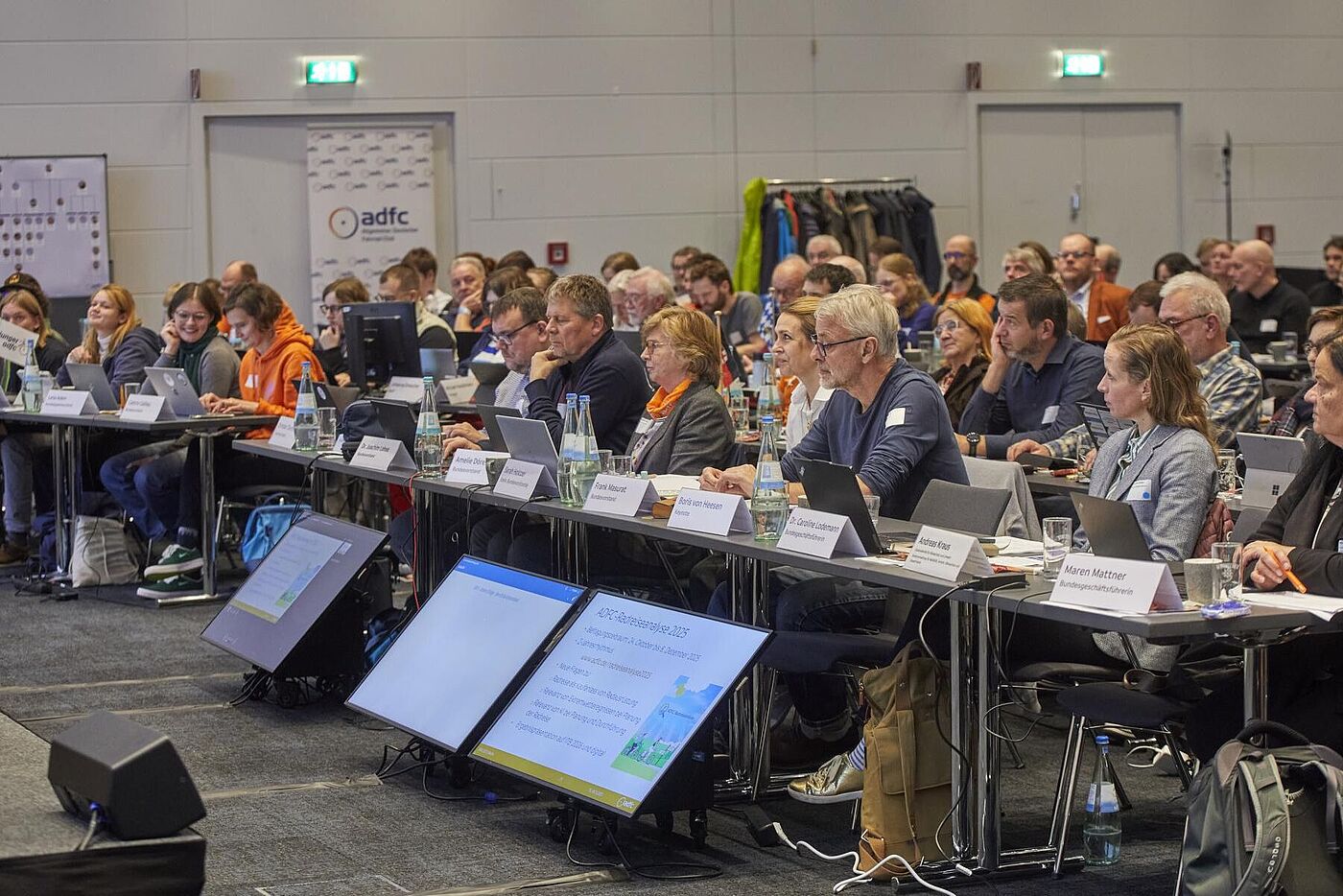 45. ADFC-Bundeshauptversammlung 2025 Teilnehmende sitzen in einem großen Konferenzraum an langen Tischen, arbeiten an Laptops und folgen der BHV 2025.